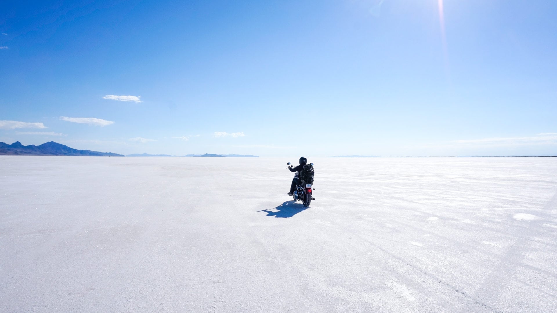 A lone motorcycle riding on bright white salt flats