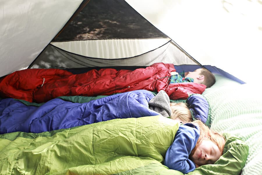 A group of kids camping outdoors in a tent