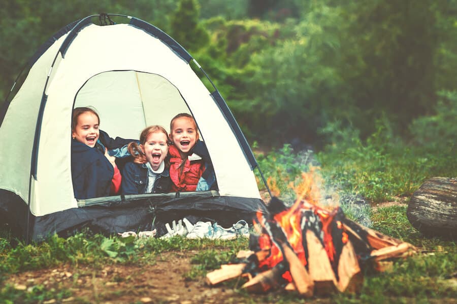 Group of kids camping in a tent around a bonfire