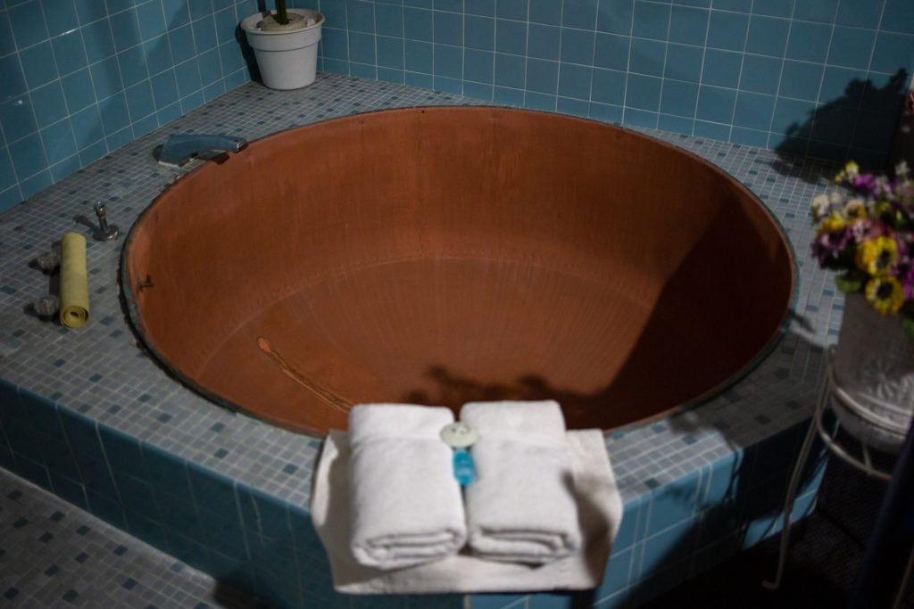 A 300-gallon copper cheese vat tub surrounded by blue tiles in the Blue Room