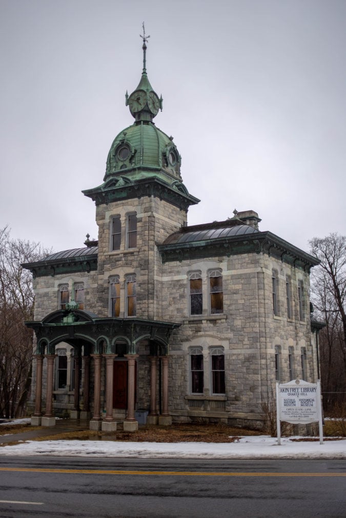 an ornate three story gray stone building with a green rotunda and clock on top