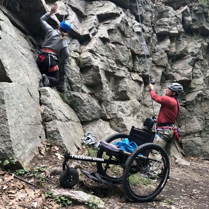 A woman in a wheelchair rock climbing
