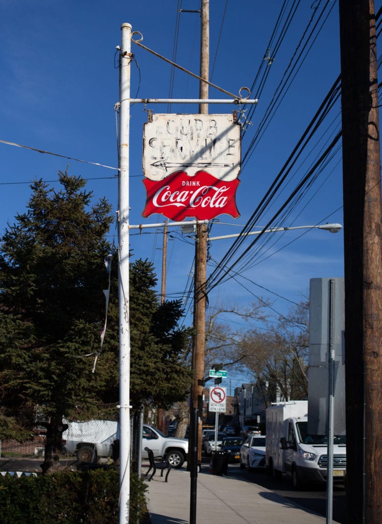A coca-cola sign advertising curb service
