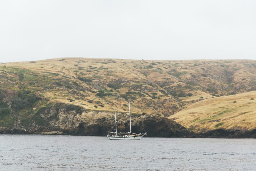 A lone sailboat rests in the harbor in front of Santa Cruz Island.