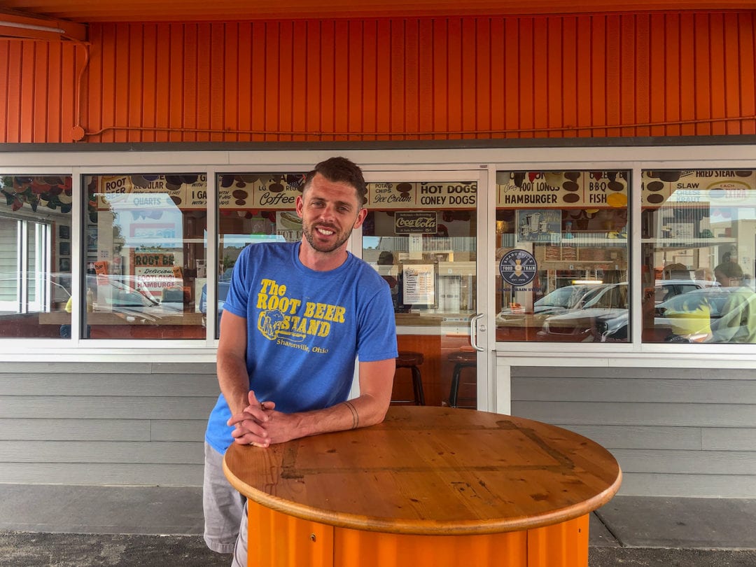 Eric Burroughs, the owner of The Root Beer Stand, leans agains a table in front of his restaurant.