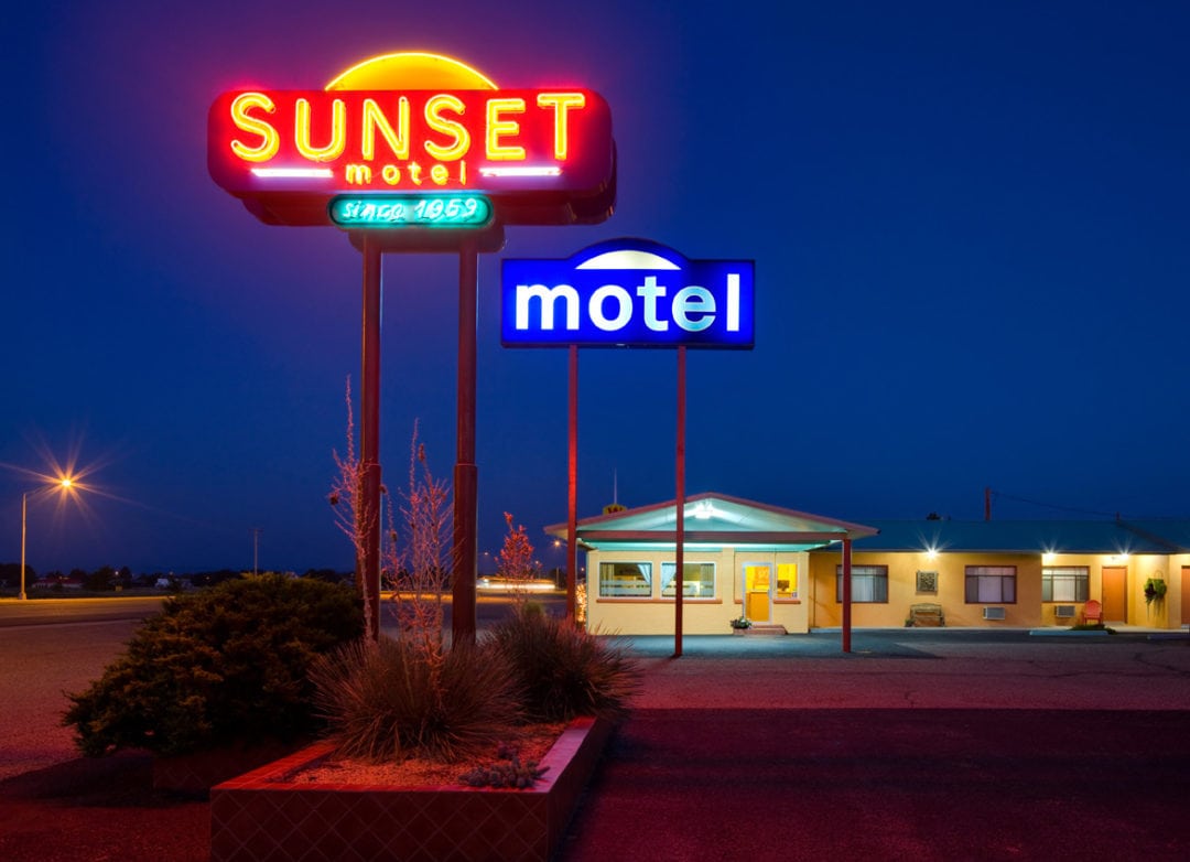 The Sunset Motel sign with its neon lit up at night.