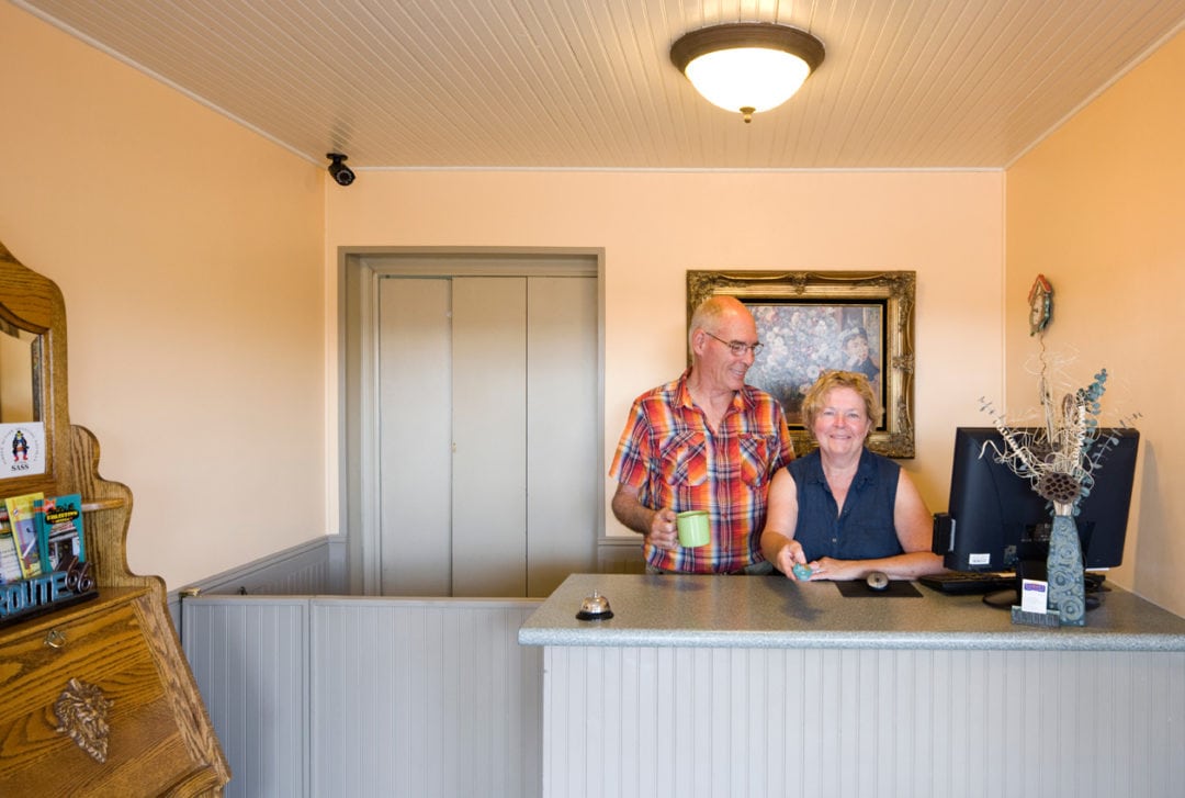 Mike and Debbie Pogue posing behind the front desk of the Sunset Motel.