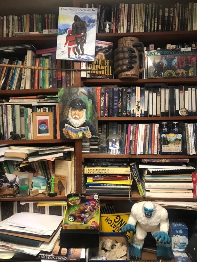 Shelves lined with bigfoot books, VHS tapes, and artifacts