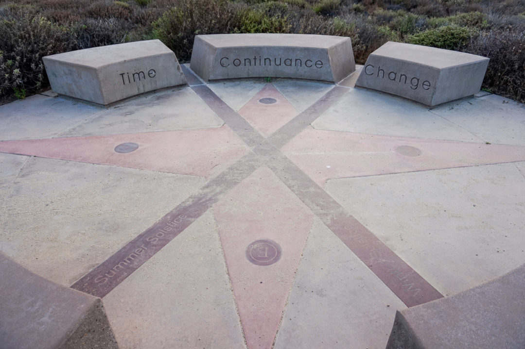 A circle of benches forms a solstice clock with the words "Time," "Continuance," and "Change" on them. 