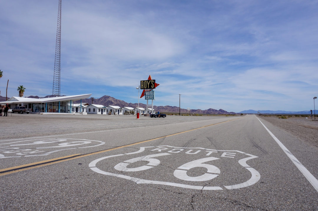 A shot of the highway with Route 66 shields and Roy's in the distance.