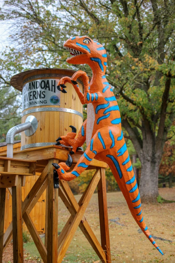 An orange and blue dinosaur perched on a water tower