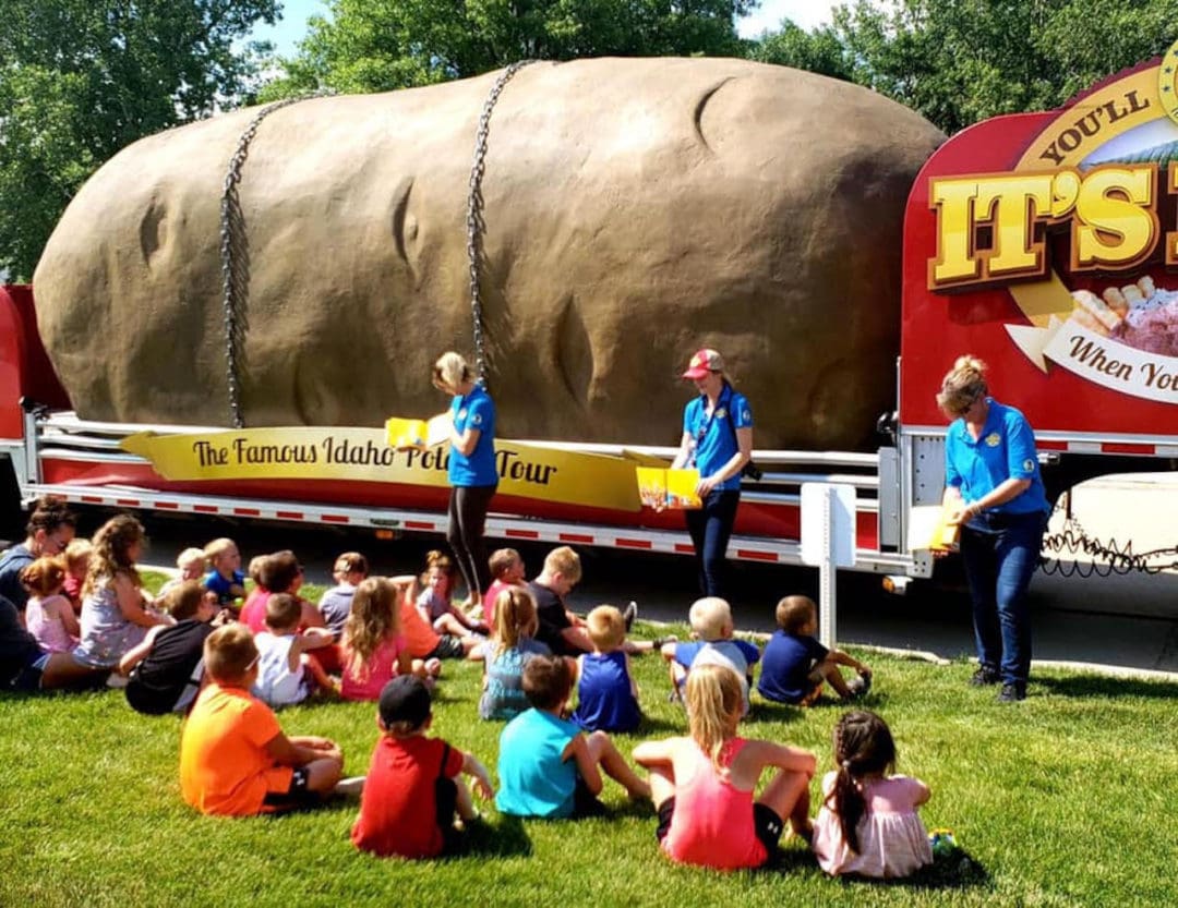 the Tater Team stands in front of the giant potato, reading to schoolchildren