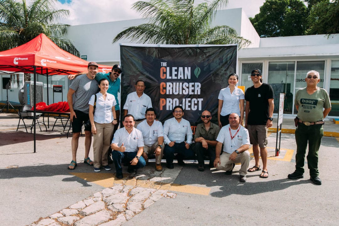 A dozen people pose in front of a Clean Cruiser Project banner