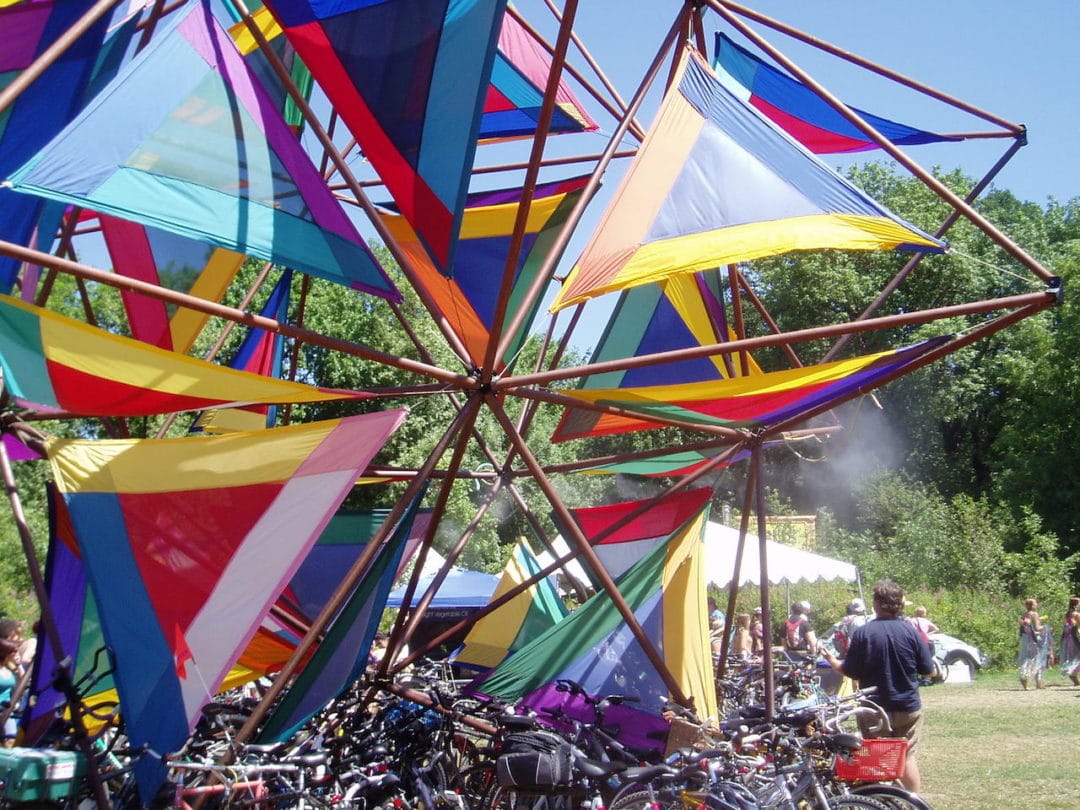 A giant rainbow pinwheel in front of dozens of bikes at the Oregon Country Fair