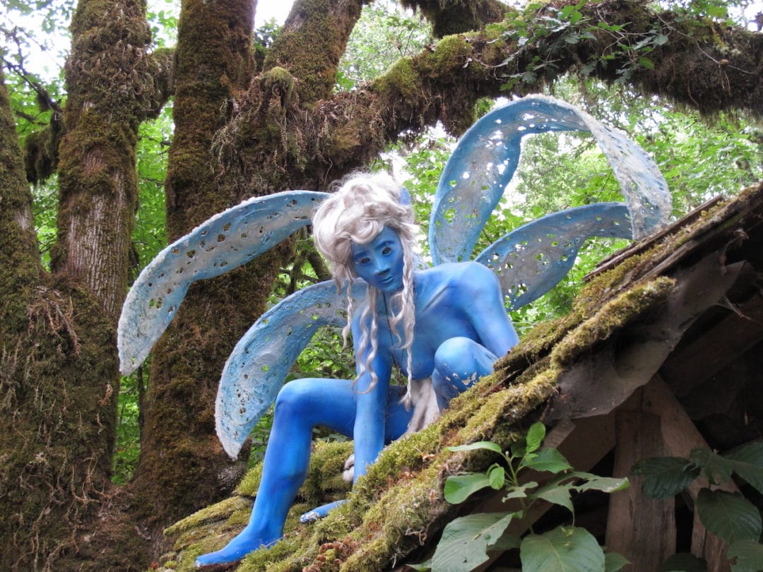 A person in a fairy costume sits perched on a roof
