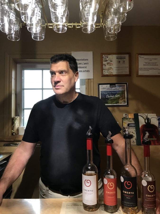 Miche stands behind a bar with his wines