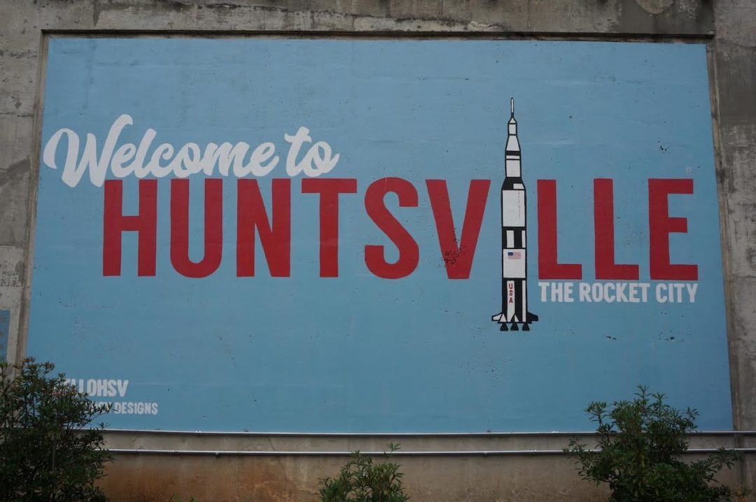 a welcome sign for huntsville, alabama, featuring a saturn v rocket in its design