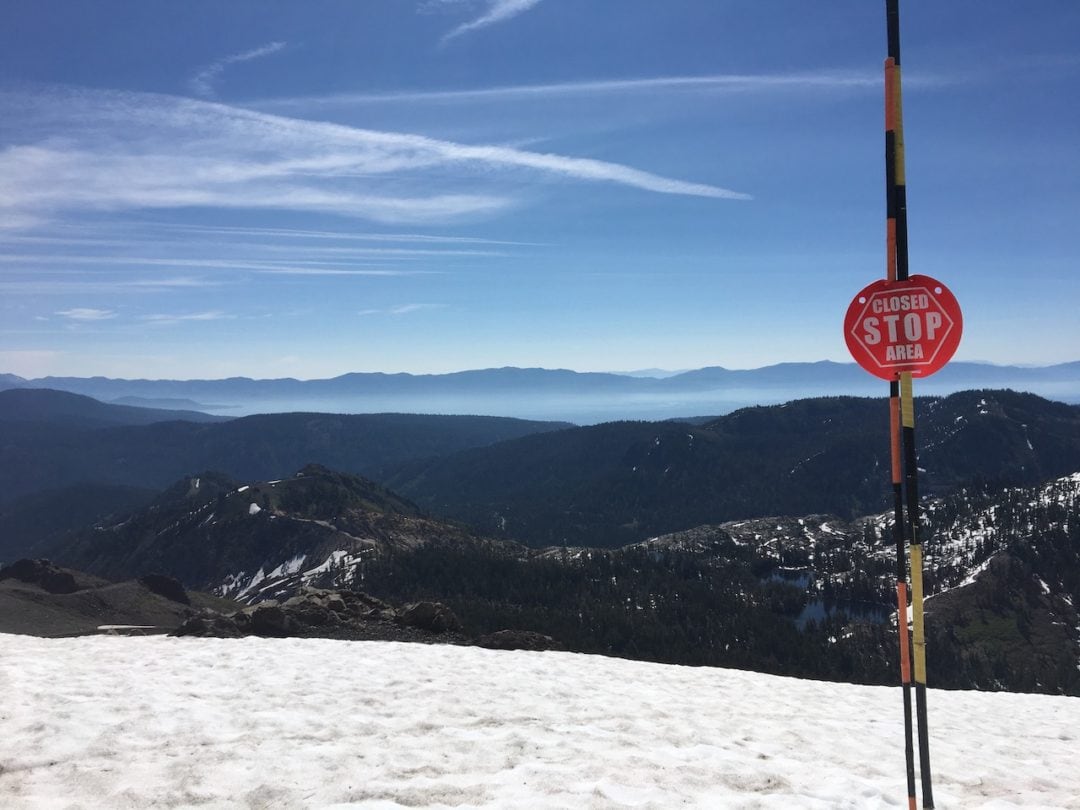 a snowpack near the edge has a sign that reads "stop: closed area"