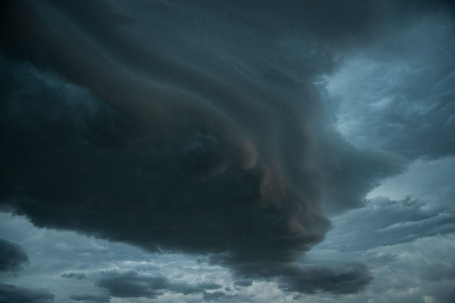 A wide, dark sky filled with funnel cloud producing supercells
