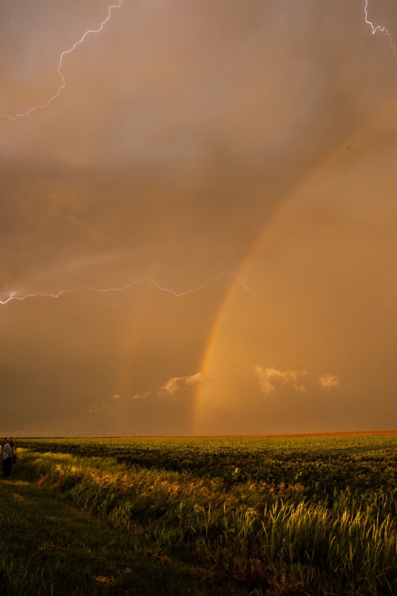 lighting and a double rainbow over a grassy field