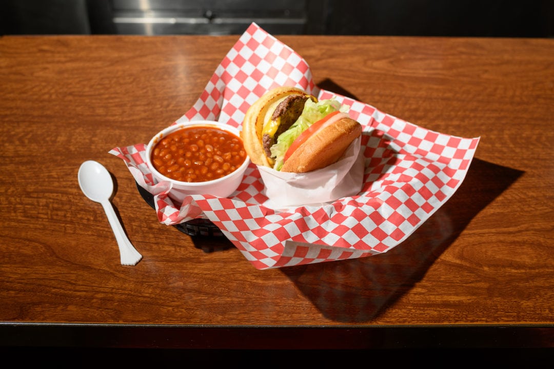 A hand-pressed burger with a side of beans