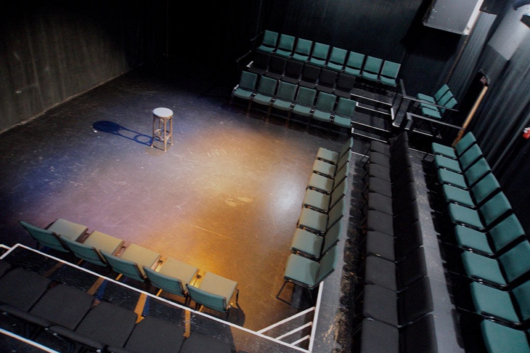 an empty stool in the middle of a small performance space