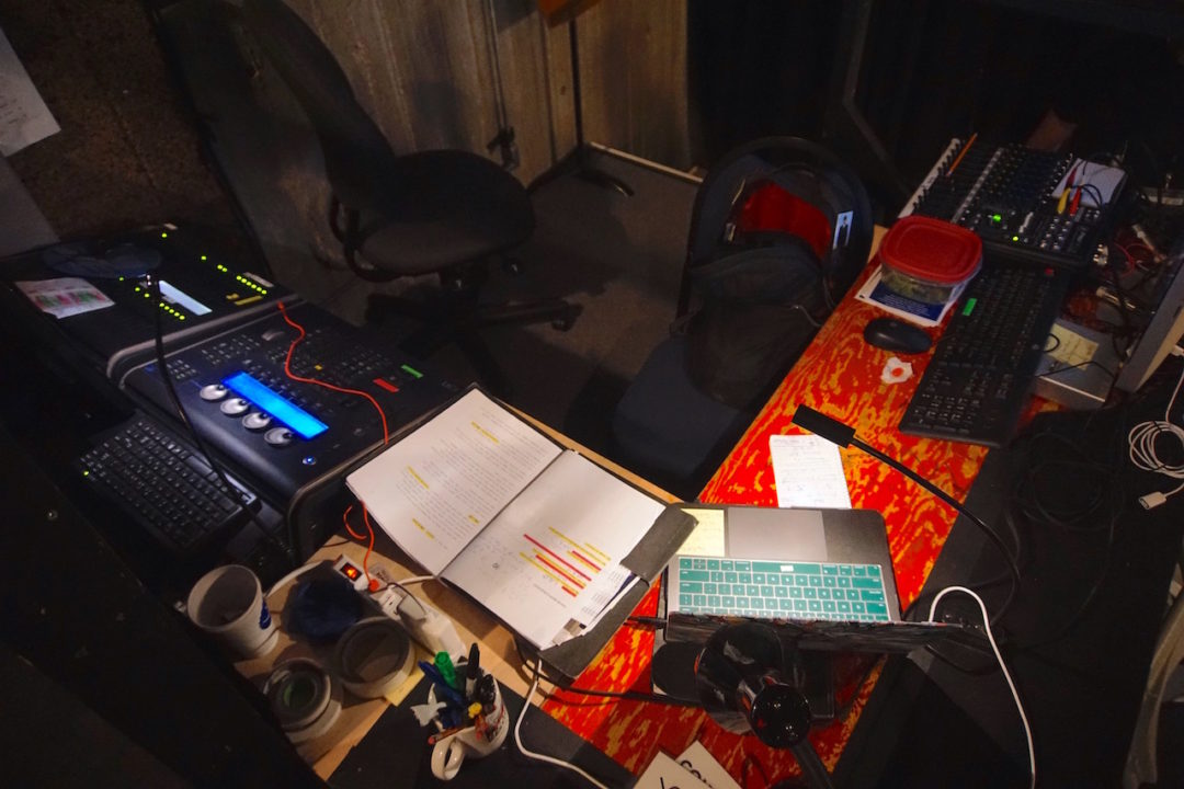 a script and a laptop lay open in front of a sound system