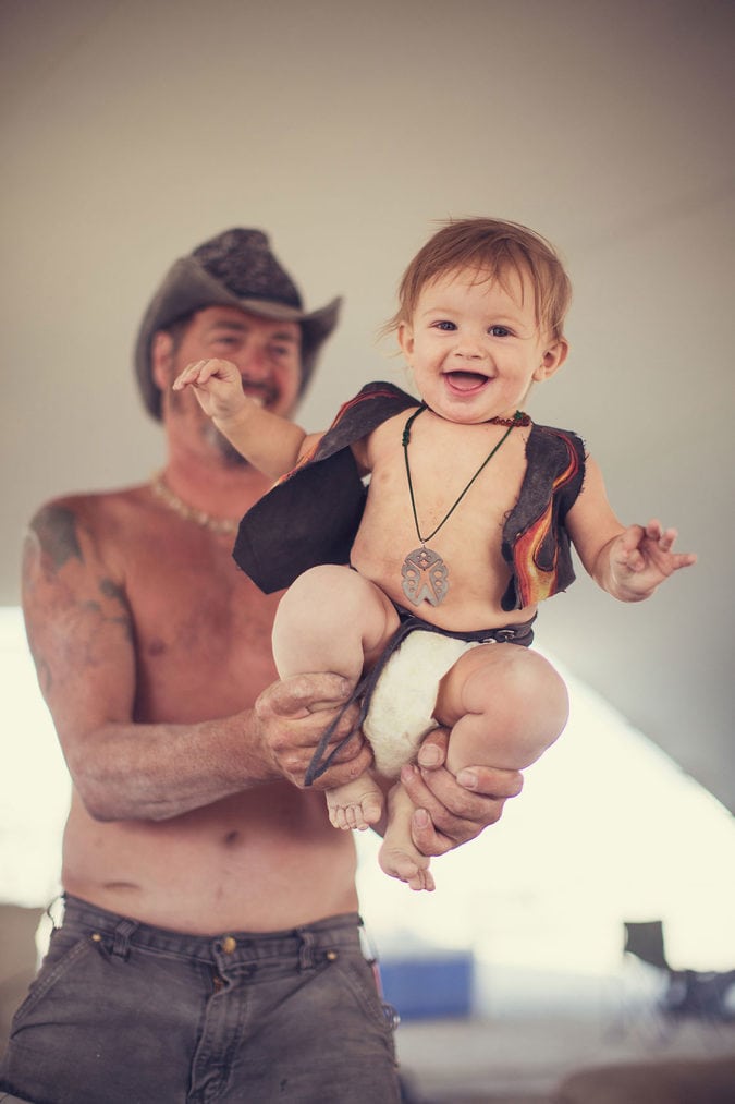 A man in a cowboy hat holding a smiling child