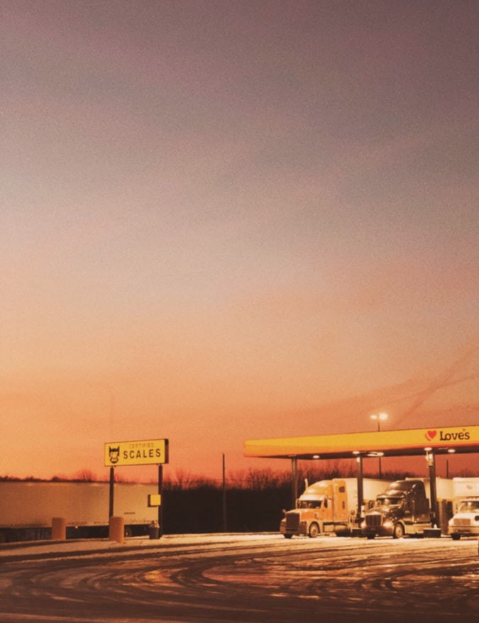 The sun sets behind a truck stop.