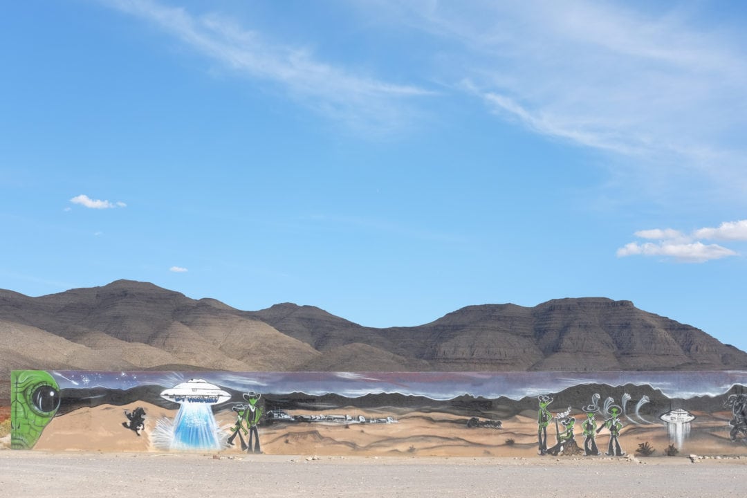 A giant tableau of alien life is painted on concrete slabs and set up near the base of the mountains.