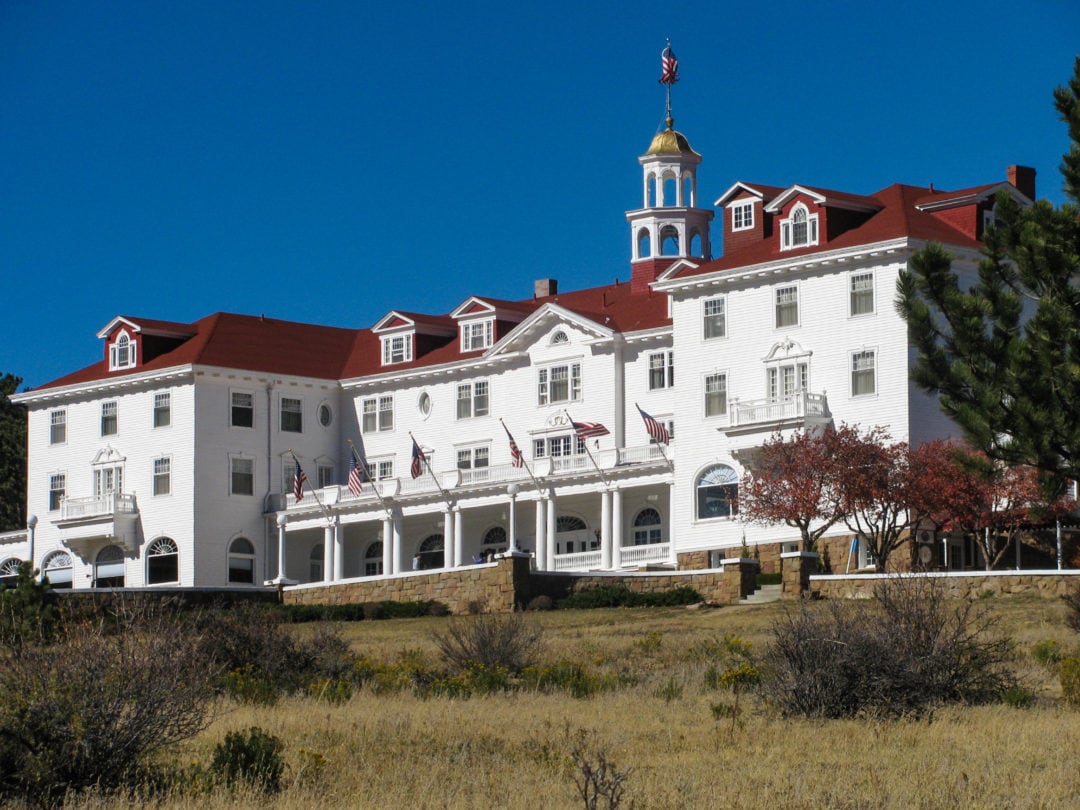 a grand white hotel with a red roof, gold leaf cupola, porch, and several american flags flying