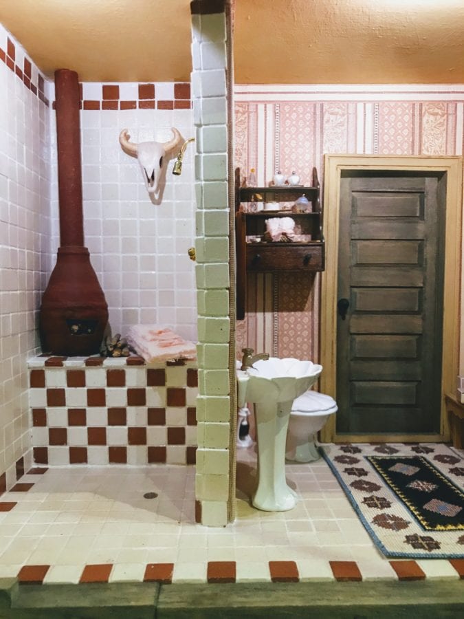 Mini bathroom with red and white tiles and a wood burning stove.
