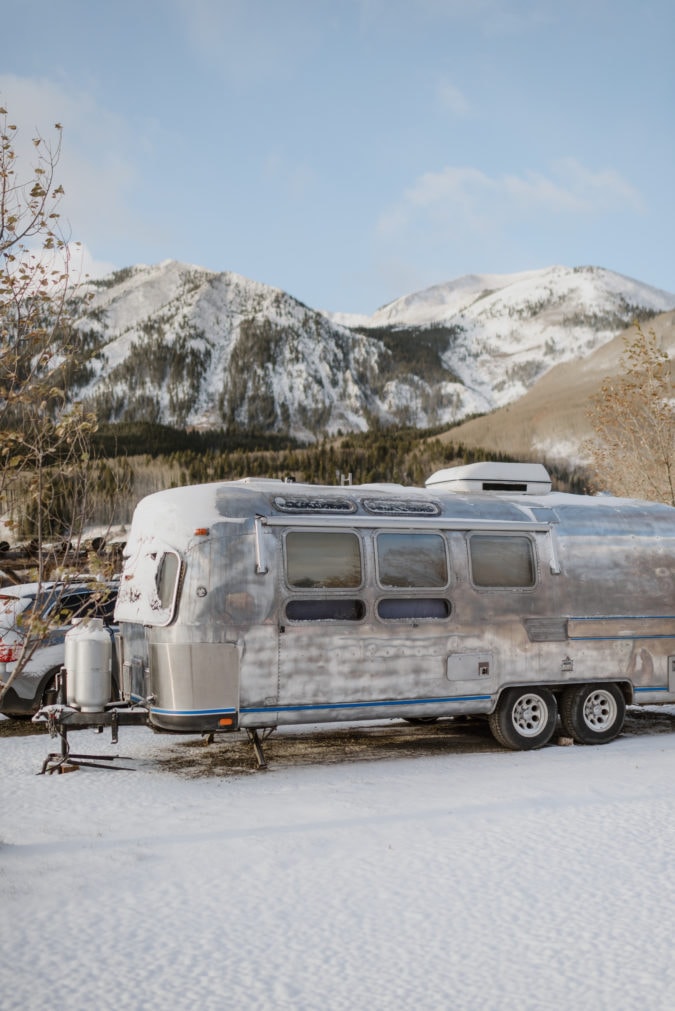 Airstream in the snow with snowy mountains in the background