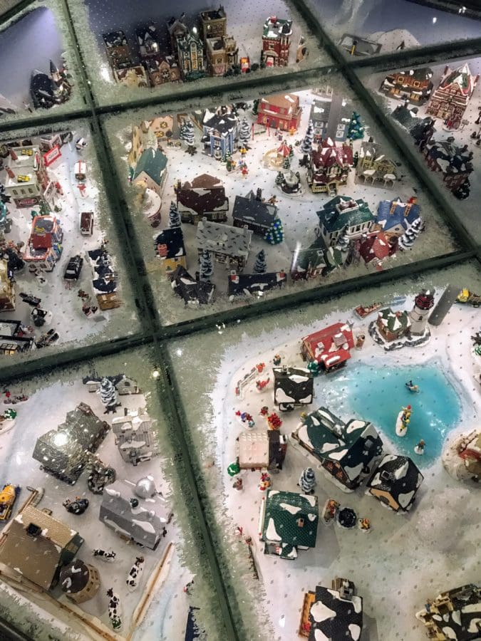 Looking down through glass windows at a mini North Pole with houses and snow.