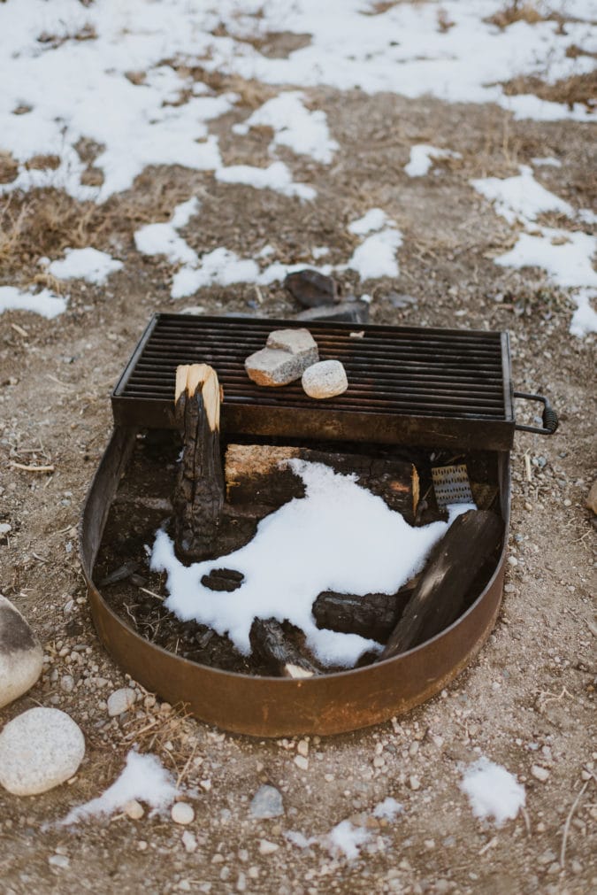 Close up of campsite fire pit with wood and snow