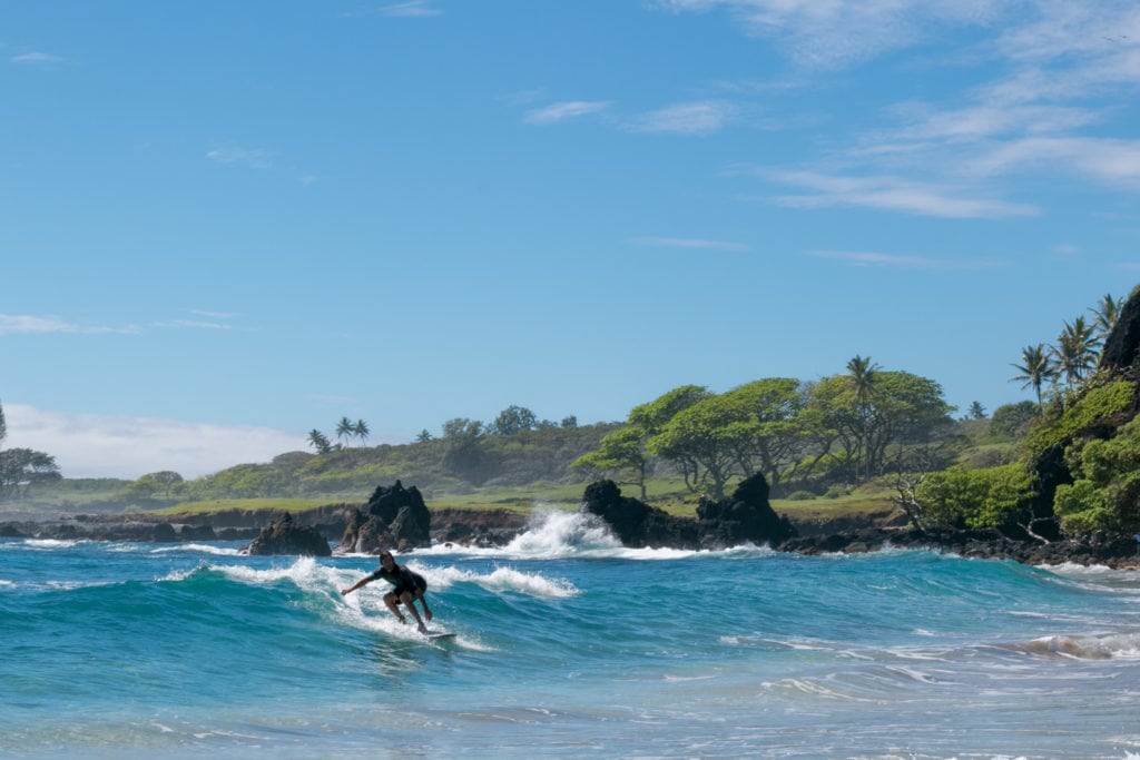 A surfer rides a wave into shore just off Hamoa Beach, considered of the world's best beaches by many renowned authors including James Michener who called it the only beach in the North Pacific that looked as if it belonged in the South Pacific.