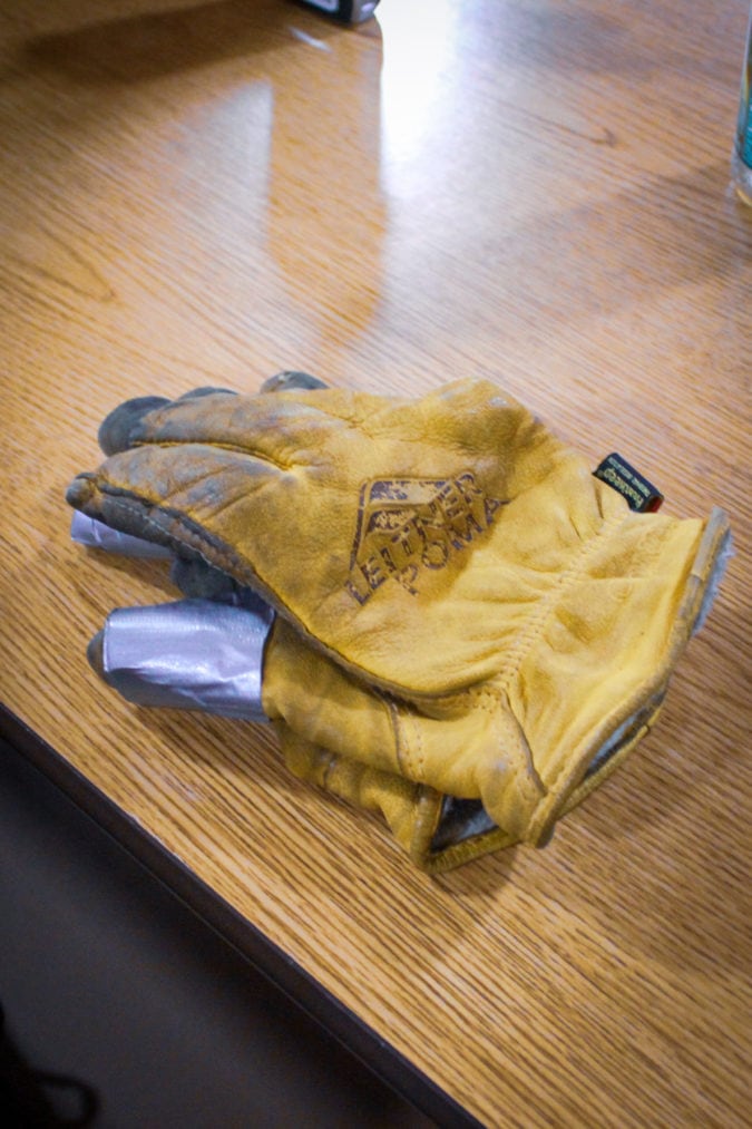 Worn yellow work gloves with duct tape