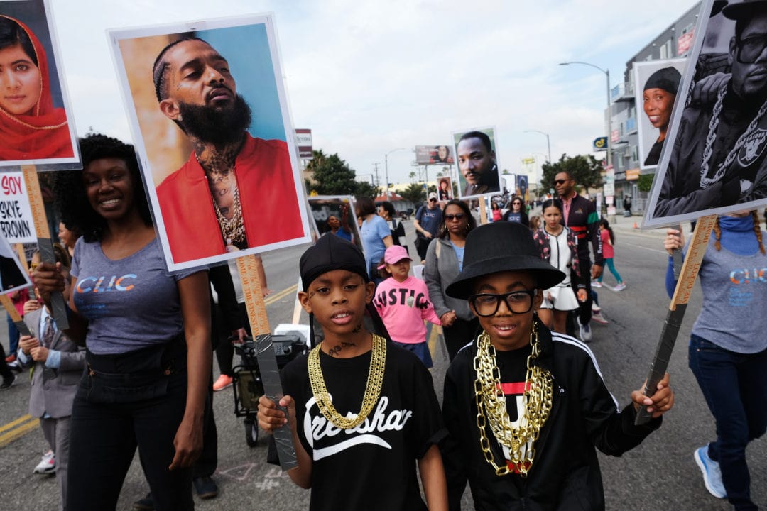 Makel and Eliel, along with other students and teachers from City Language Immersion Charter School, march in the parade dressed as their cultural heroes. Makel marches as rapper Nipsey Hussle and Eliel is dressed as rapper Darryl McDaniels of Run-DMC. The dual language school prepares children for a lifetime of critical thinking, meaningful work, and ongoing service to causes greater than themselves.