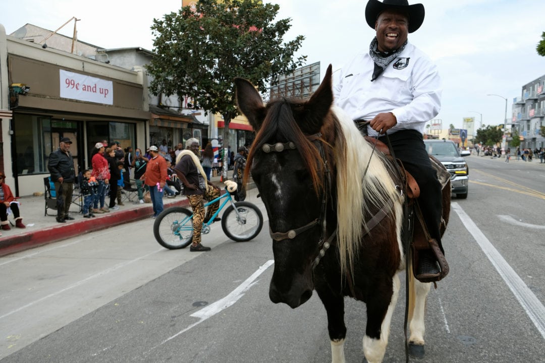 Greg sits mounted on his horse Babe. He rides in the parade with other cowboys from the equestrian organization Urban Saddle, a non-profit ranch based in South Gate. Focusing on mentoring inner-city youth, their objective is to build hope and opportunities through the equine experience and the cowboy code of ethics. They teach students horsemanship, respect, integrity, and responsibility as an alternative to the streets and gang life.