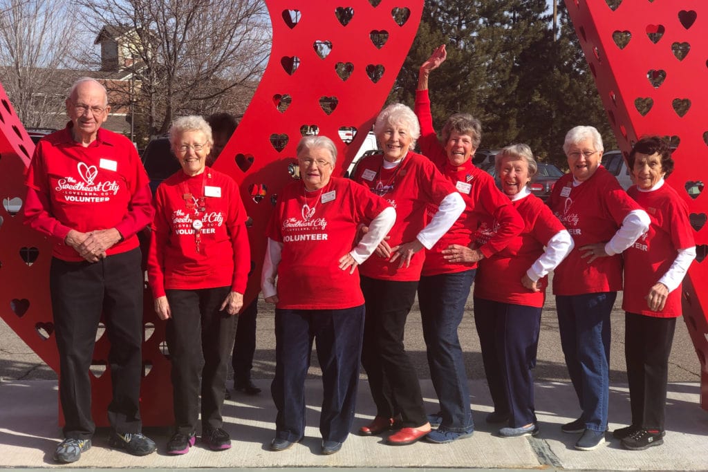 Volunteer stampers pose in front of the giant love lock statue in Loveland, Colorado.