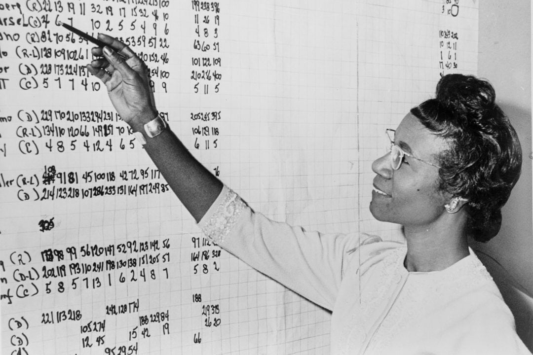 Chisholm reviewing political statistics in 1965.