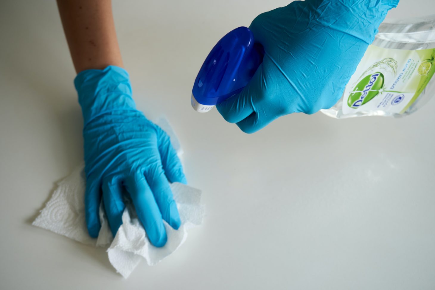 Cleaning surface with rubber gloves on using cleaner and paper towel 