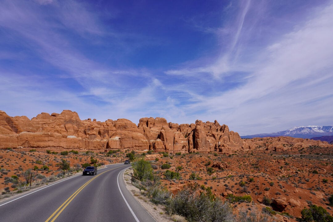 A car driving on a road surrounded by towering red rocks