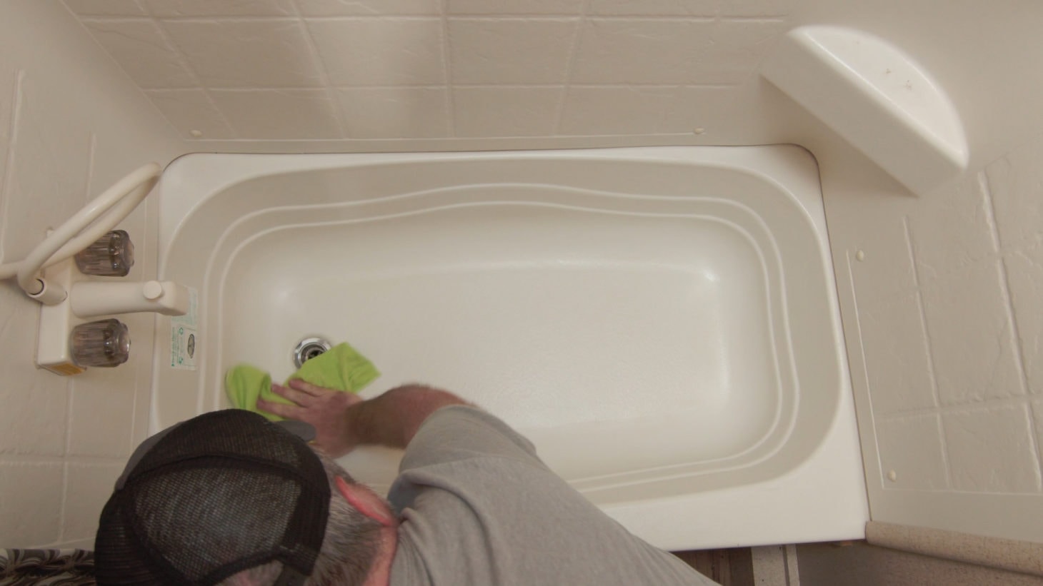 Man scrubbing bathtub in an RV bathroom