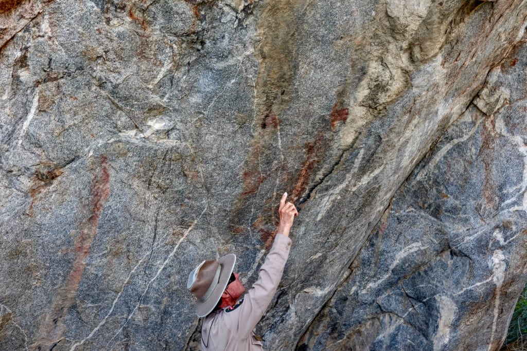 Hepburn points out pictographs spread across one boulder.
