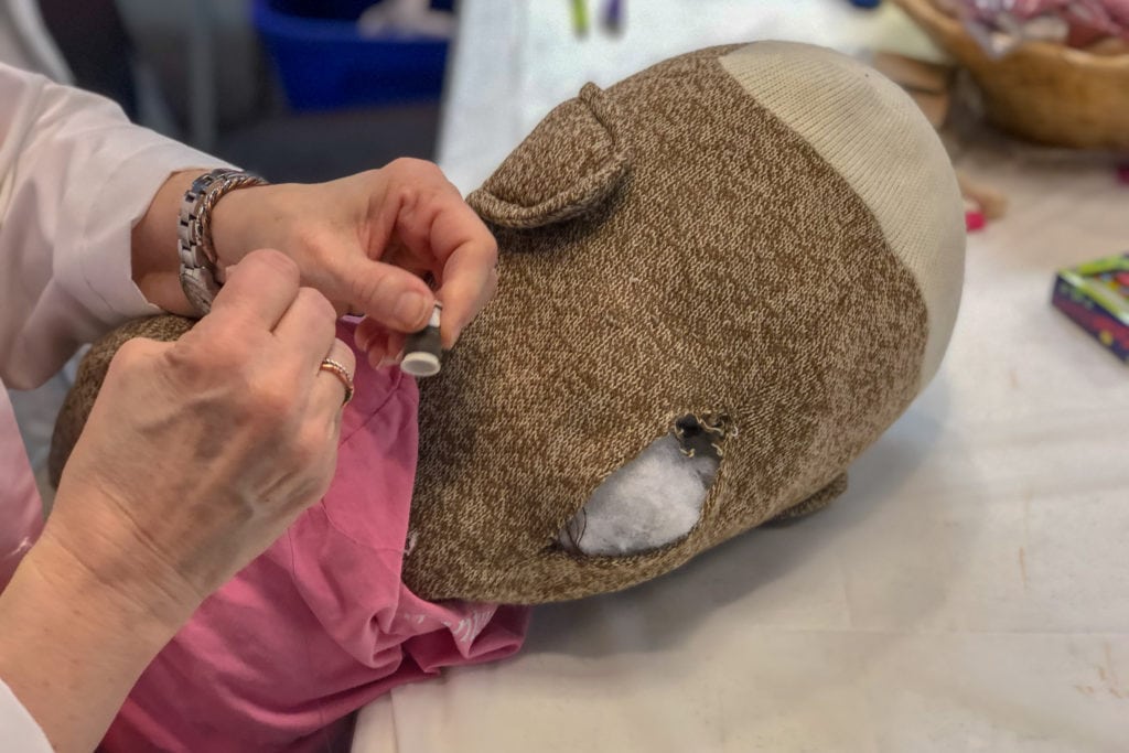 Poffinbarger repairs a child’s sock monkey toy. She spent the day sewing up rips, tears, and reattaching sock monkey limbs