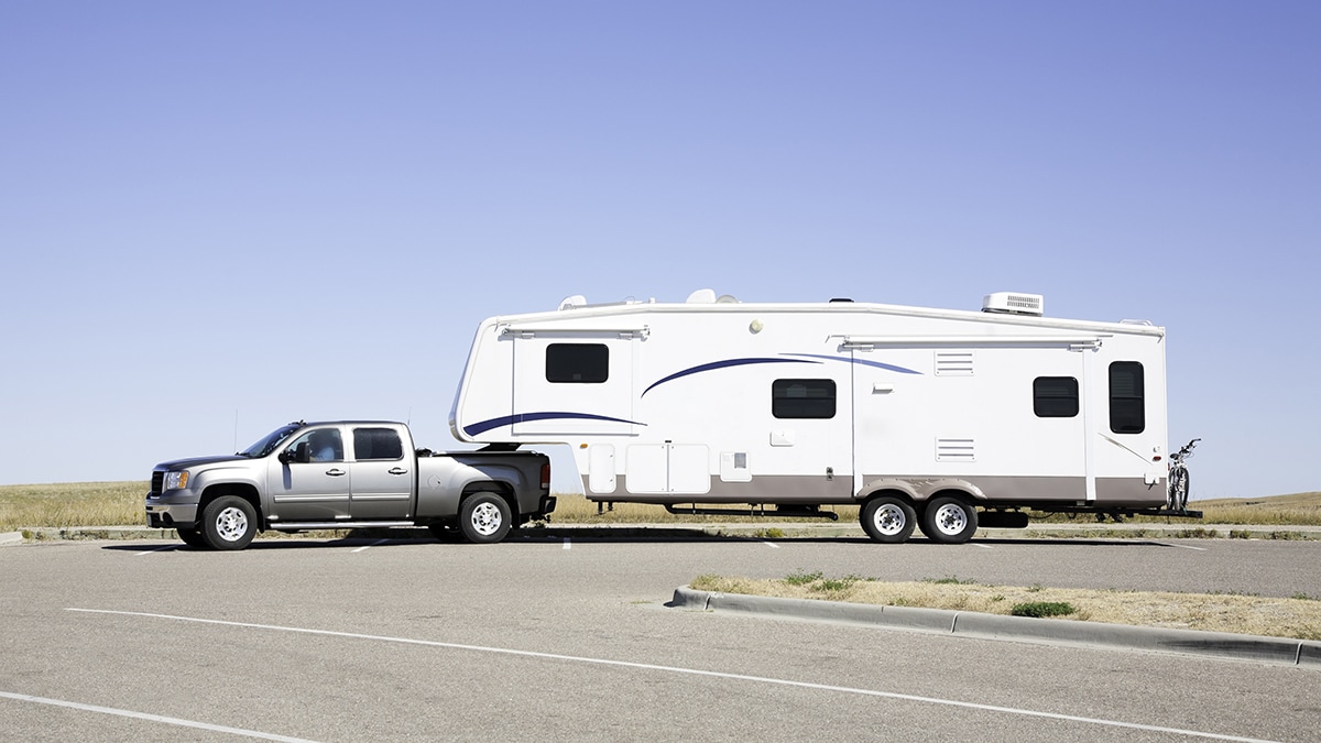 Fifth wheel RV being towed by a truck in a parking lot
