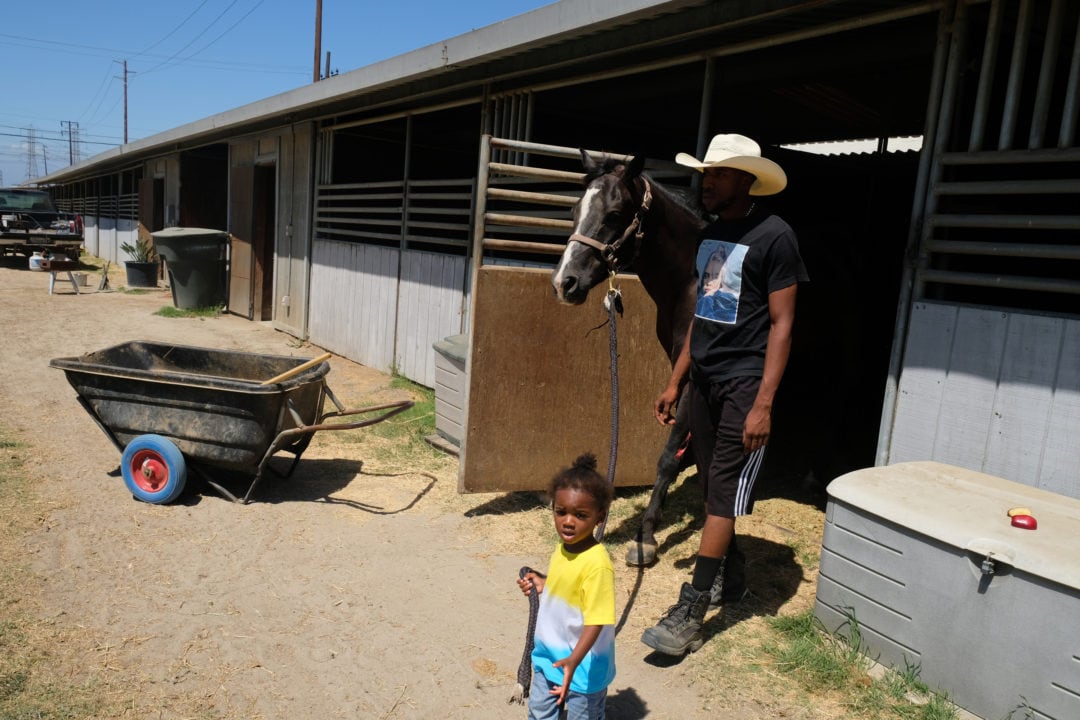 Jacob Ellis, the stable manager, leads a horse to be saddled with his son Messiah. 