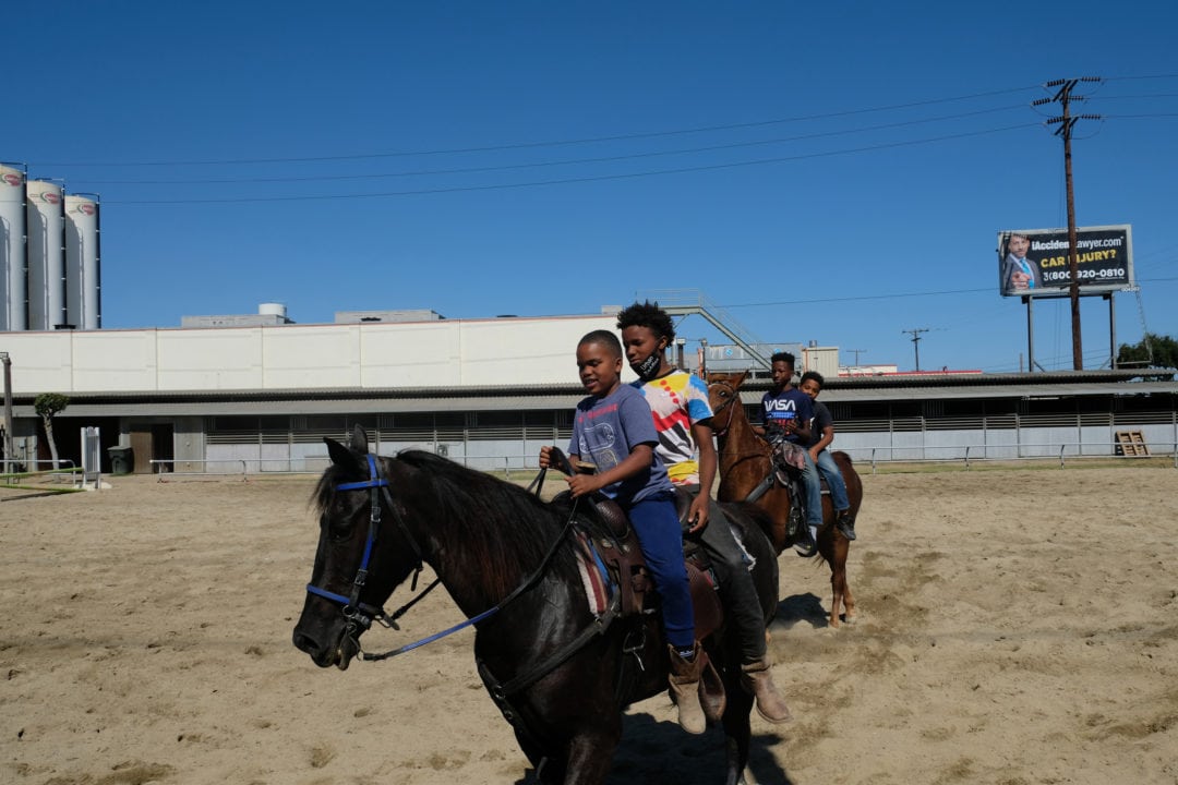 Four young cowboys having fun riding tandem in the saddle. 