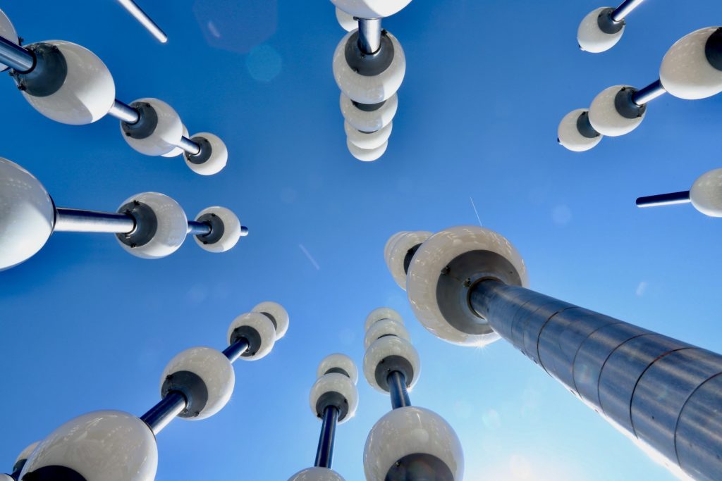 Looking up at a collection of artistic light poles against a blue sky